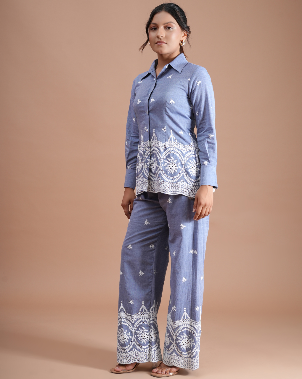 Woman wearing a blue traditional outfit with white patterns on a beige background