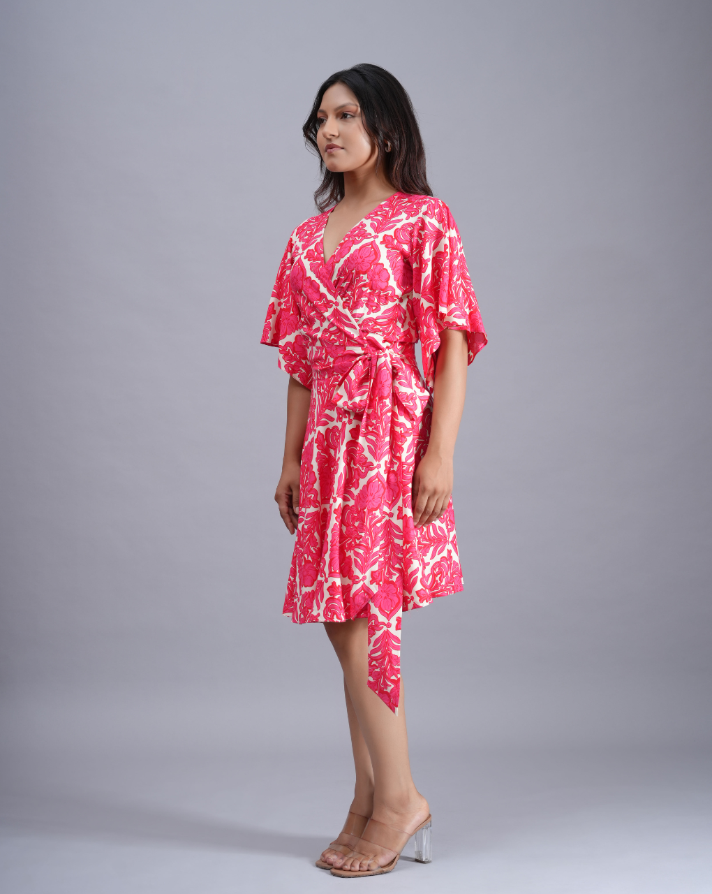 Woman wearing a pink and white patterned dress on a gray background