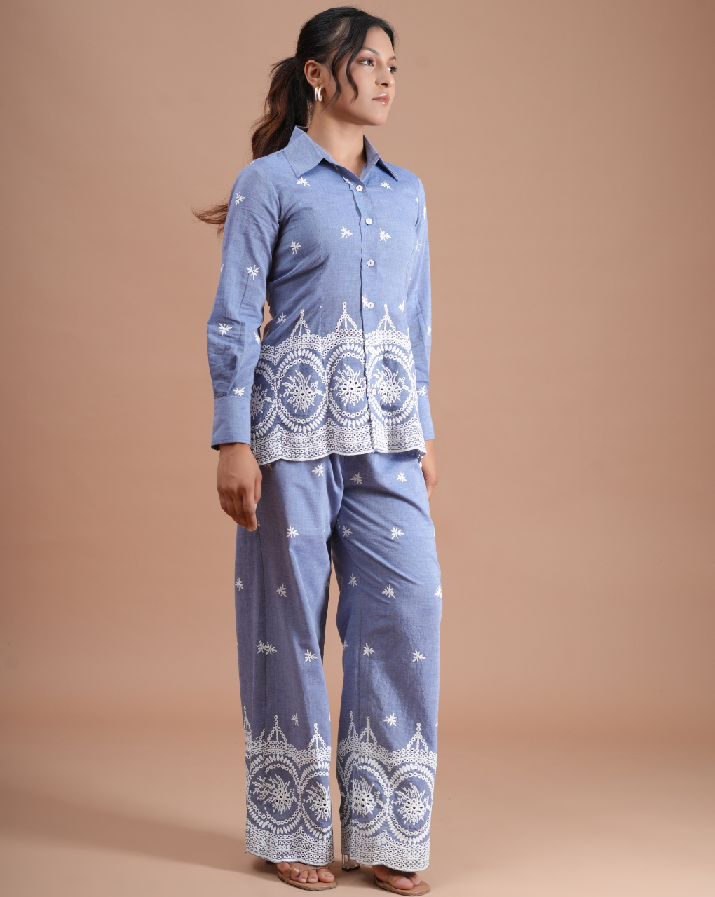 Woman wearing a blue traditional outfit with white patterns on a beige background