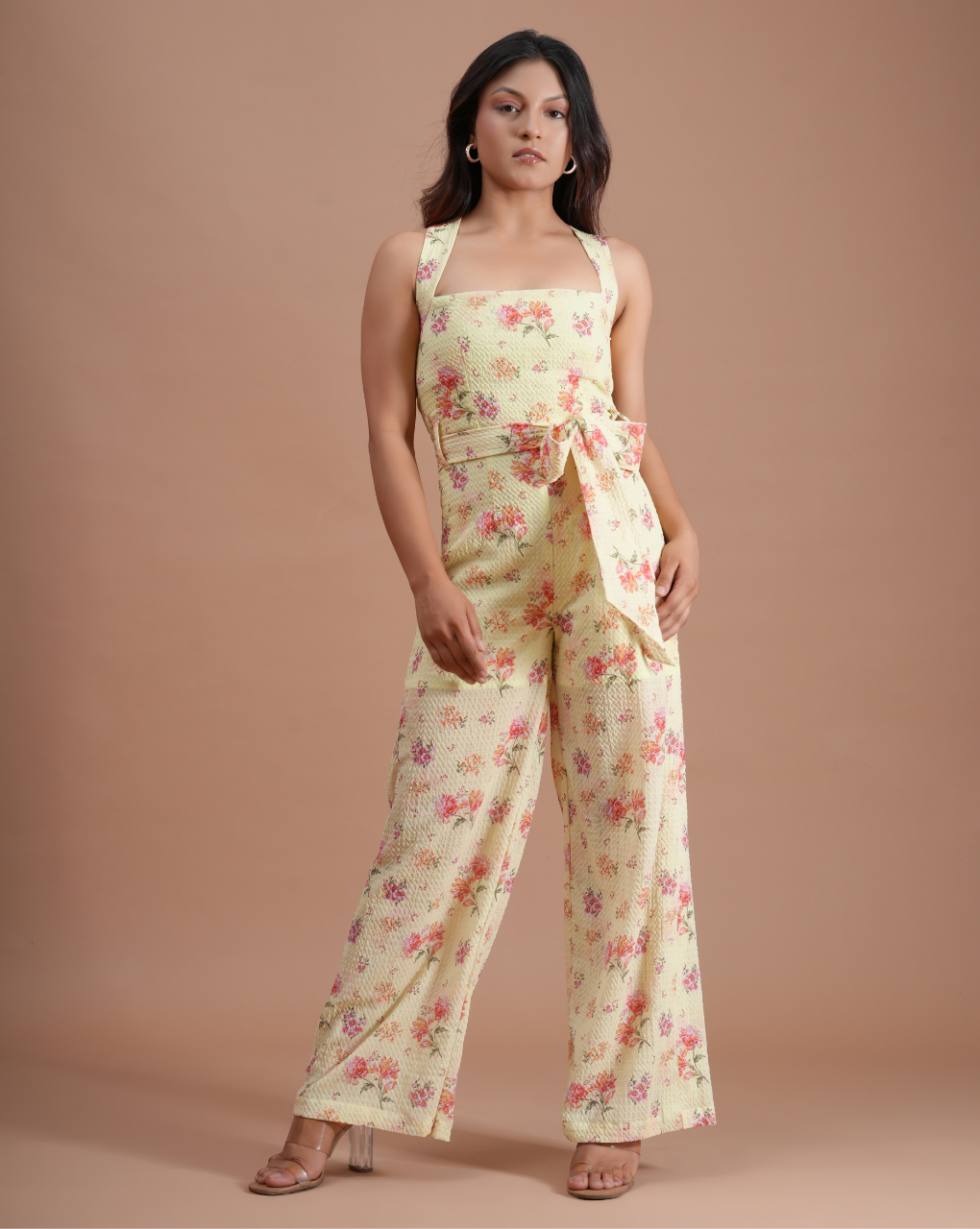 Woman wearing a floral jumpsuit on a beige background