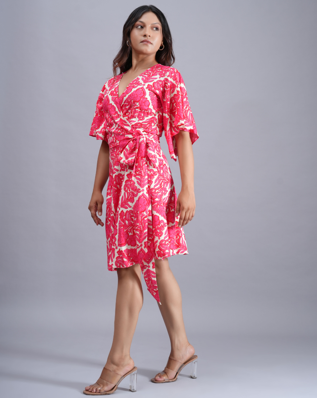 Woman wearing a pink and white patterned dress on a gray background