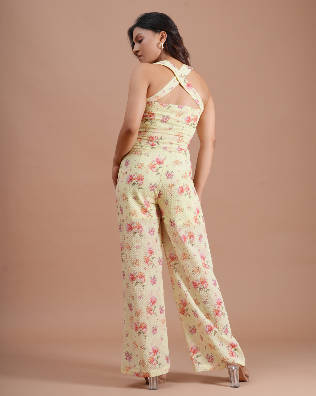 Woman wearing a floral jumpsuit against a beige background