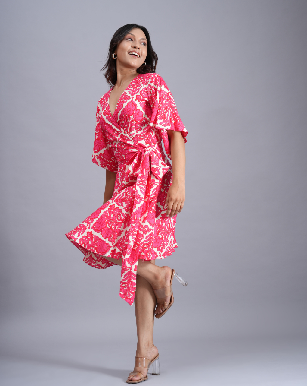 Woman wearing a pink and white patterned dress on a gray background