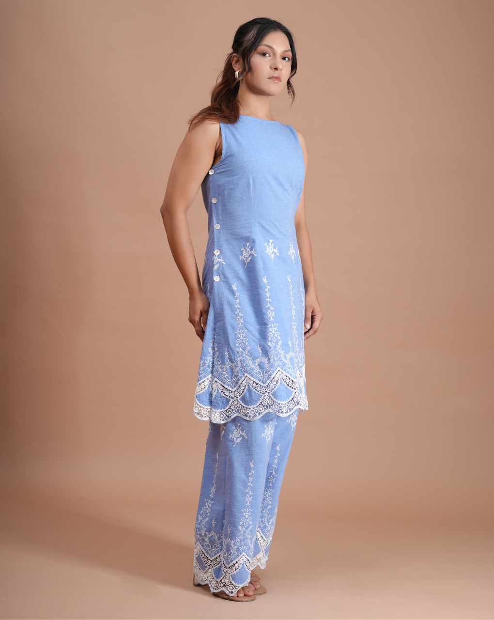 Woman wearing a light blue dress with lace details on a beige background