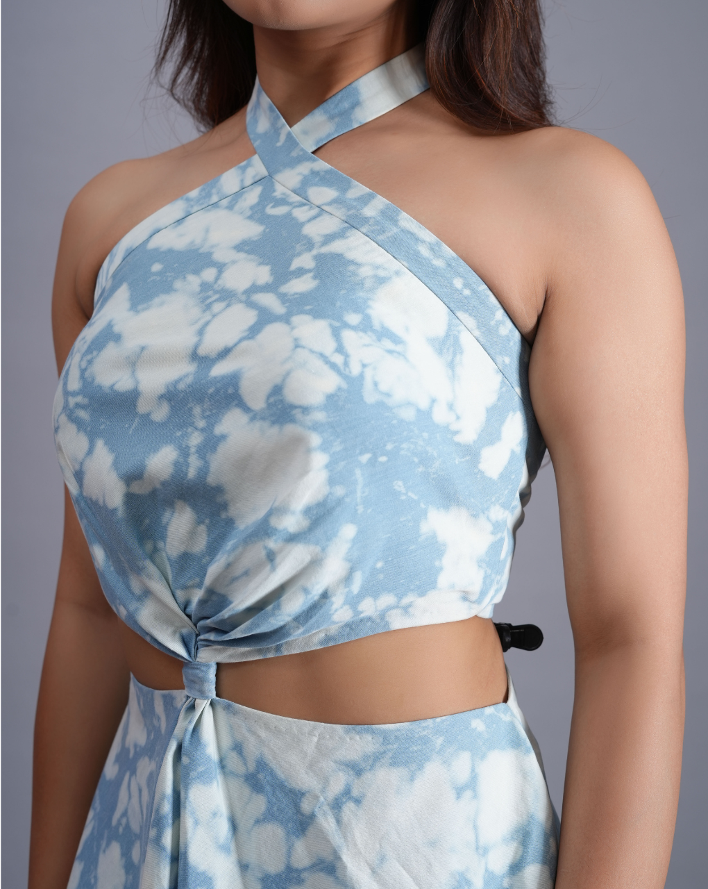 Woman wearing a blue and white tie-dye halter top with a gray background