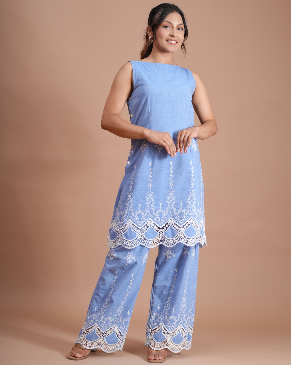 Woman wearing a light blue embroidered outfit on a beige background