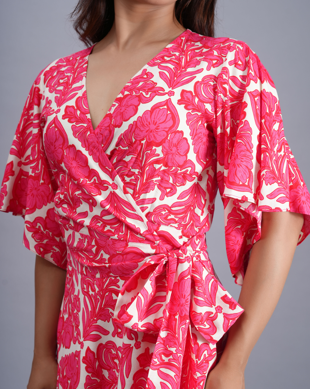 Woman wearing a pink and white floral dress against a gray background