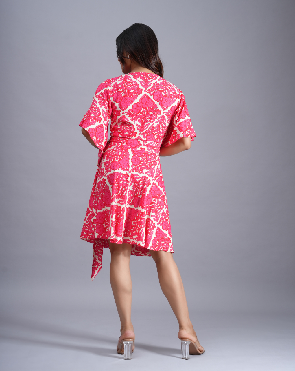 Woman wearing a pink and white patterned dress on a gray background