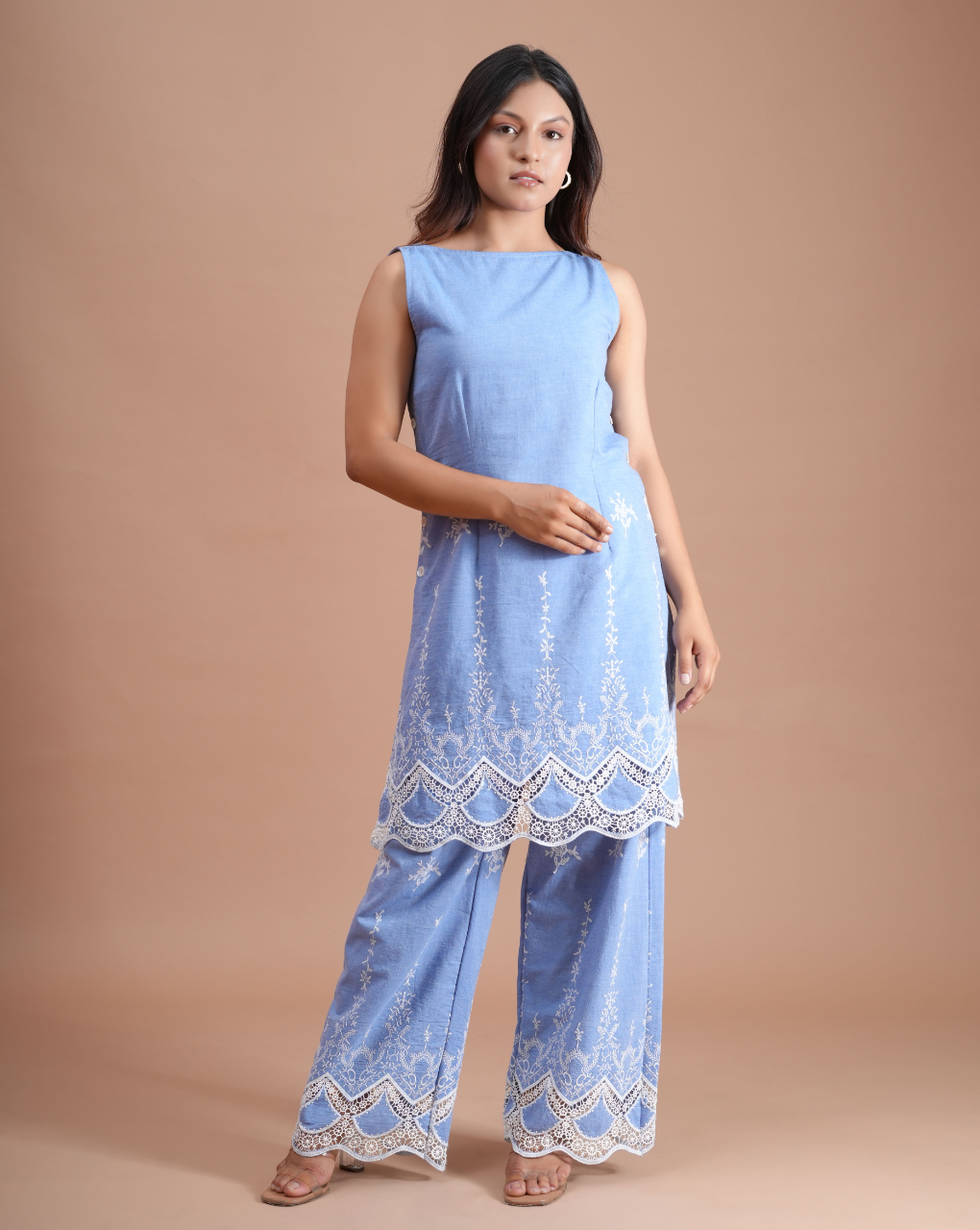 Woman wearing a light blue outfit with lace details on a beige background