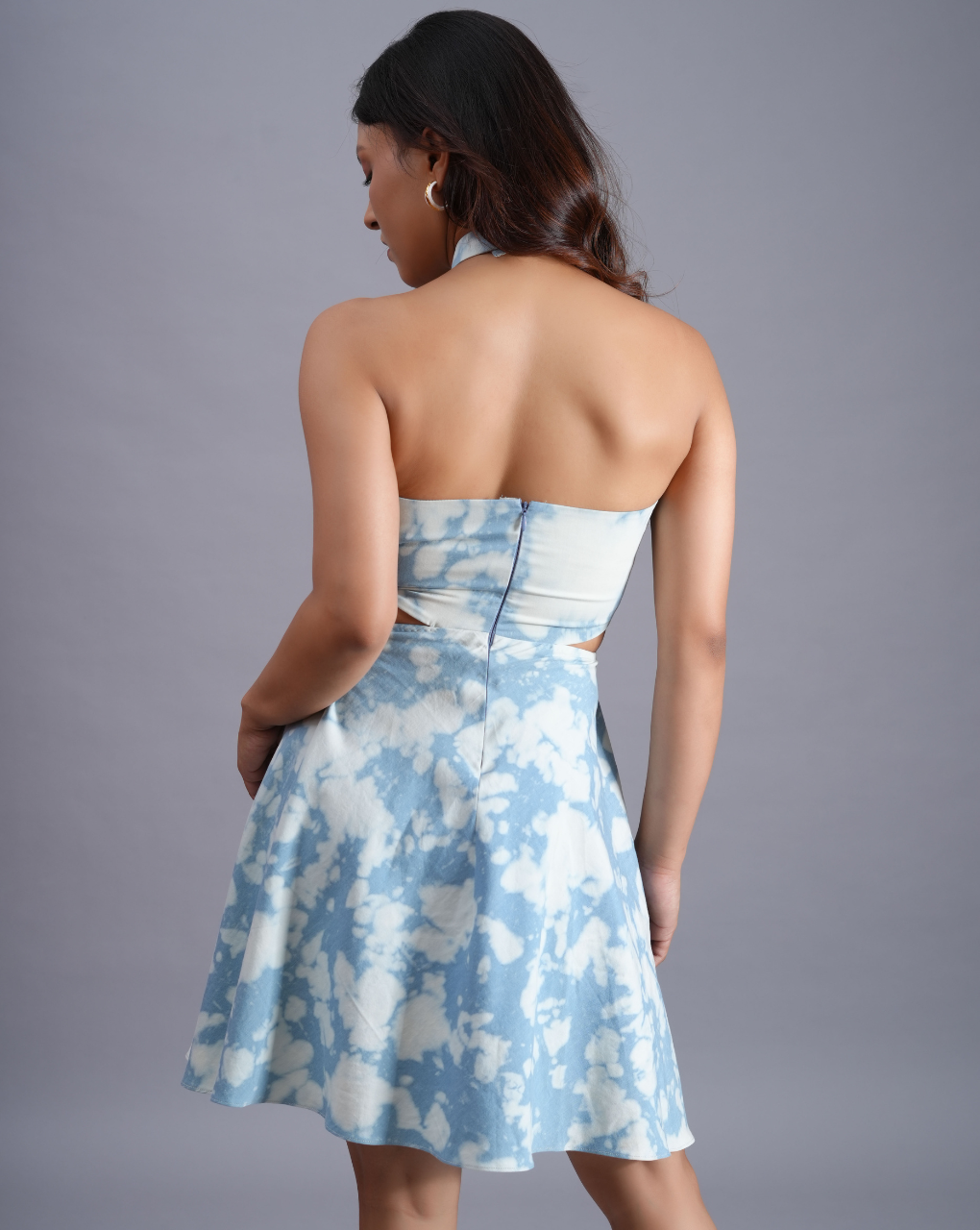 Woman wearing a strapless dress with blue and white floral pattern on a gray background